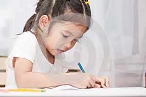 Cute asian child girl having fun to draw and paint with crayon