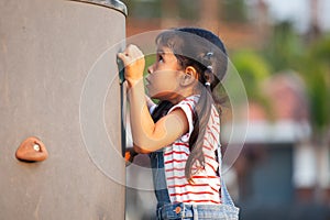 Cute asian child girl play and climbing on the rock wall