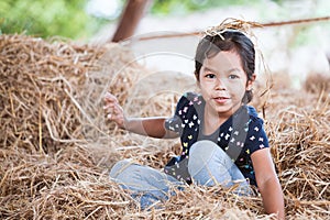 Cute asian child girl having fun to play with hay stack