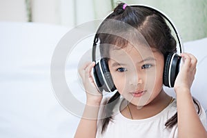 Cute asian child girl in headphones listening the music