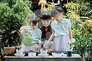 Cute asian child girl helping mother planting or cutivate the plants. Mom and daughter engaging in gardening at home. Happy activi