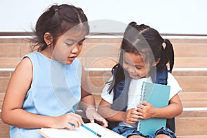 Cute asian child girl and her sister reading a book