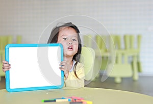 Cute asian child girl holding empty white blackboard in kids room