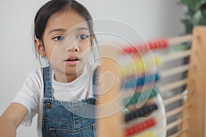 Cute asian child girl learning to count using an abacus in the classroom at kindergarten