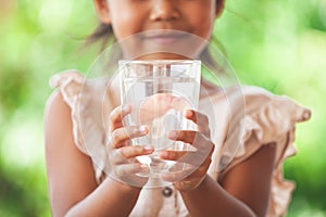 Cute asian child girl like to drink water and holding glass of fresh water photo
