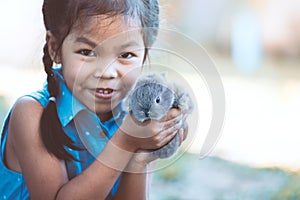 Cute asian child girl playing with bunny rabbit with love and tenderness