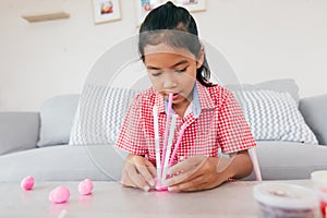 Cute asian child girl playing and creating with playdough and straws.