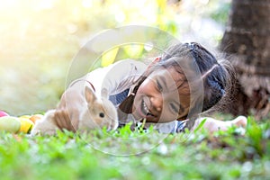 Cute asian child girl playing with little bunny rabbit with love and tenderness