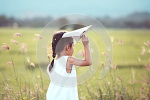 Cute asian child girl playing toy paper airplane in the field