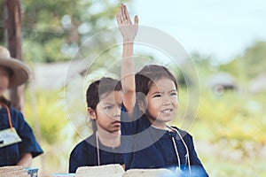 Cute asian child girl raising her hand in the air to answer