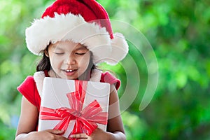 Cute asian child girl in santa red hat holding Christmas gift