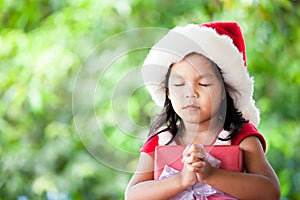 Cute asian child girl in santa red hat holding Christmas gift