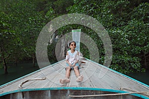 Cute asian child girl sitting on the head of wooden longtail boat travel on the sea go to the amazing island and lagoon