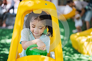 Cute asian child girl smile play toy car on school or kindergarten yard or playground. Healthy summer activity for children. Child