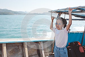 Cute asian child girl standing on the longtail boat travel on the sea go to the amazing island and enjoying with beautiful nature