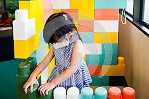 Cute Asian child girl standing play with big building blocks in room toys at kindergarten