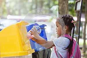 Cute asian child girl throwing plastic glass in recycling trash