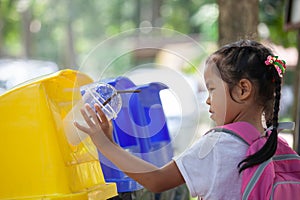 Cute asian child girl throwing plastic glass in recycling trash