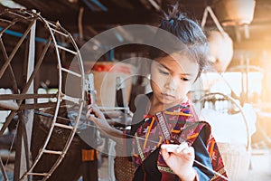 Cute asian child girl using traditional wooden spinning wheel