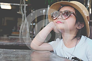 Cute Asian child girl wearing sunglasses and a hat