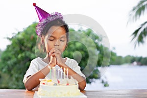 Asian child girls make folded hand to wish the good things for her birthday in birthday party