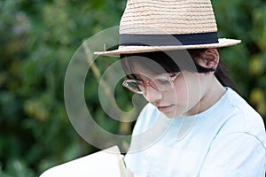 cute asian child reading a book in the garden at summer