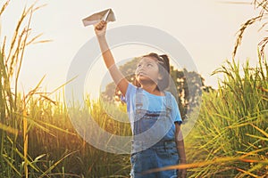 cute asian children playing paper airplane at rice field