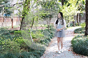 Cute Asian Chinese pretty girl wear student suit in school hold a book walking