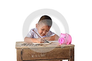Cute asian country boy Make a note of income receipts and coins with piggy bank isolated on white background