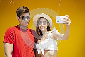 Cute asian couple taking selfie with smartphone over orange background