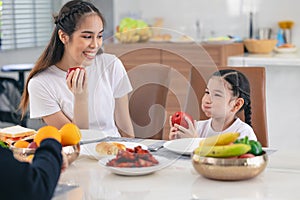 Cute Asian daughter eating red apple fruit and healthy food with girl teen healthcare lifestyle at home