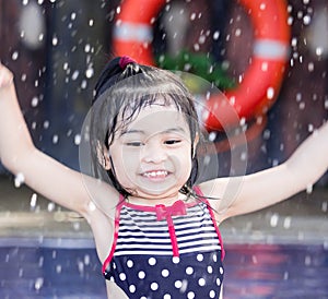 Cute asian female toddler child while playing and splashing water in a swimming pool