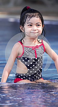 Cute asian female toddler child while playing on water in a swimming pool