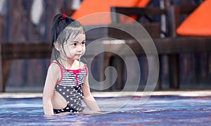 Cute asian female toddler child while playing on water in a swimming pool