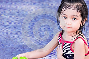 Cute asian female toddler child while playing with water on a swimming pool