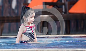 Cute asian female toddler child while playing on water in a swimming pool