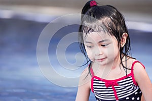 Cute asian female toddler child while playing on water in a swimming pool