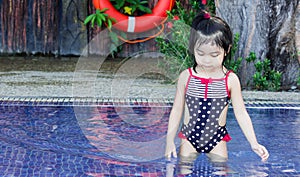 Cute asian female toddler child while playing with water on a swimming pool