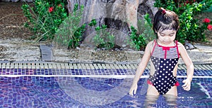 Cute asian female toddler child while swimming and playing on a swimming pool