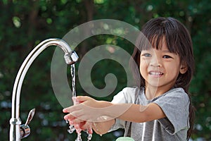 A cute Asian girl aged 4 to 8 years old, washing her hands with soap from the tap. To clean her hands Frequent hand washing with s