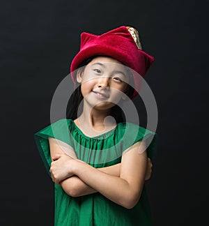 Cute asian girl child dressed in fairy hat and green dress on a black background