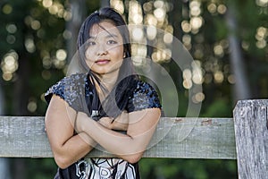 Cute asian girl on a fence on blurred woods background