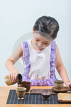 Cute Asian Girl While playing a cup of tea and a cup of sake on