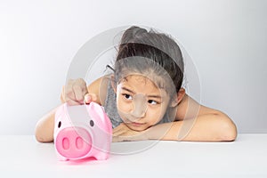 Cute asian girl putting coin into piggy bank