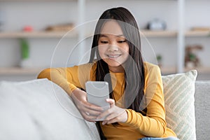 Cute asian girl schooler playing games on cellphone, panorama