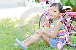 Cute asian girl sit near the bicycle.