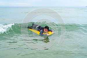 Cute asian girl wearing a black swimsuit running on the waveboard surf in the sea on a bright day