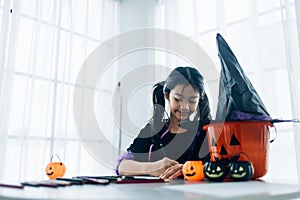 Cute asian girl in witch costume making jack-o-lantern for Halloween party