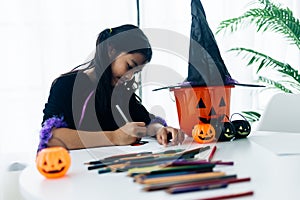 Cute asian girl in witch costume making jack-o-lantern for Halloween party
