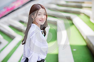 Cute Asian high school student girl in the school uniform with braces on her teeth standng and smiles confidently while she looks